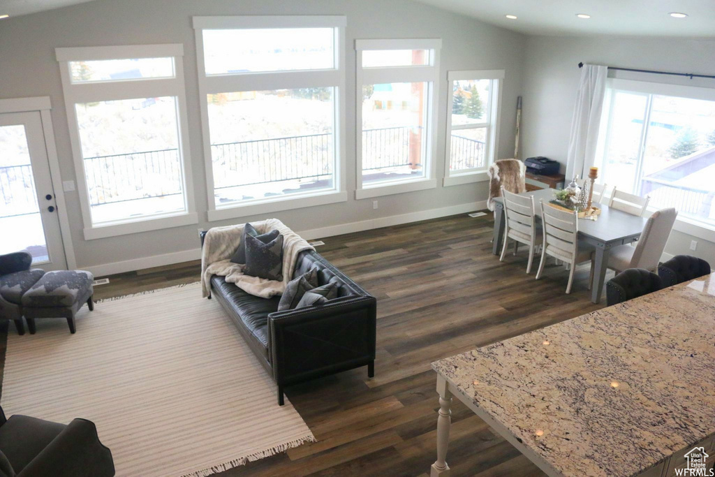 Living room featuring lofted ceiling, dark wood-type flooring, baseboards, and recessed lighting