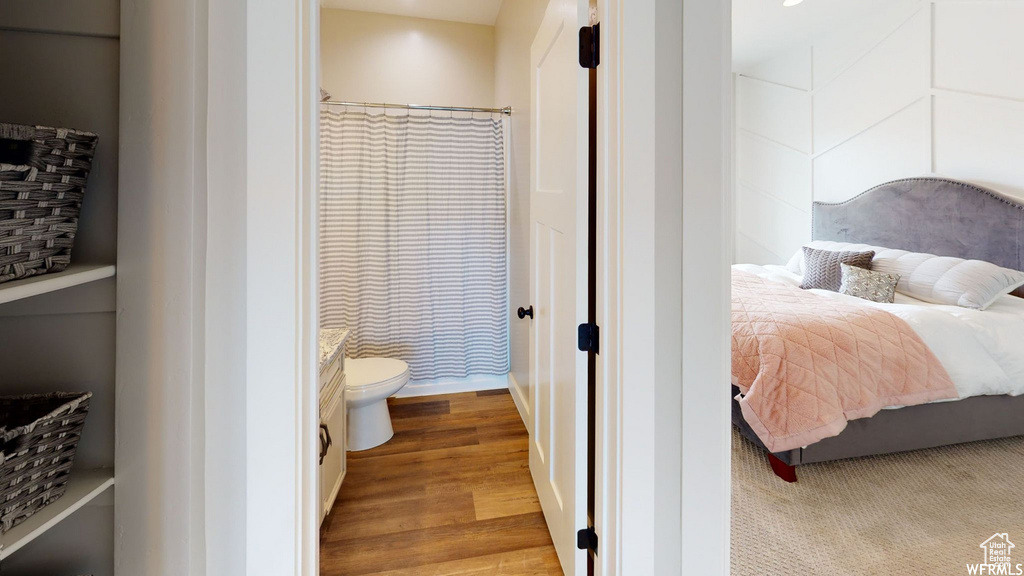 Bedroom with ensuite bath and wood finished floors