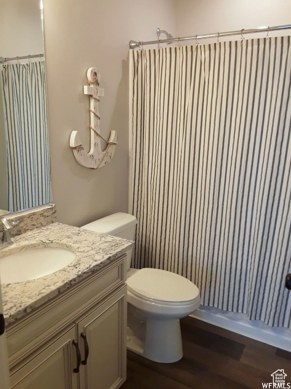 Full bathroom featuring toilet, a shower with shower curtain, wood finished floors, and vanity