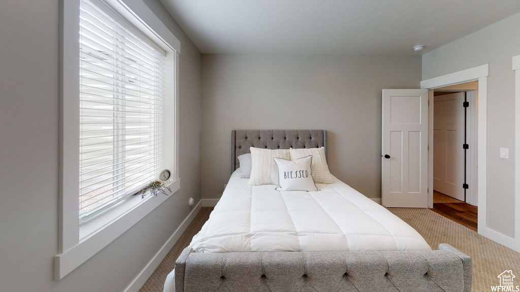 Carpeted bedroom featuring multiple windows and baseboards