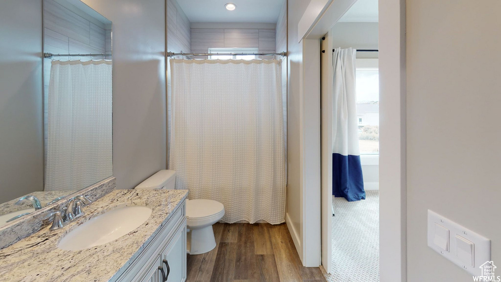 Bathroom featuring toilet, curtained shower, wood finished floors, and vanity