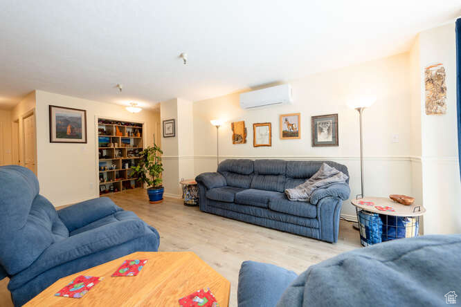 Living room featuring a wall mounted air conditioner and wood finished floors
