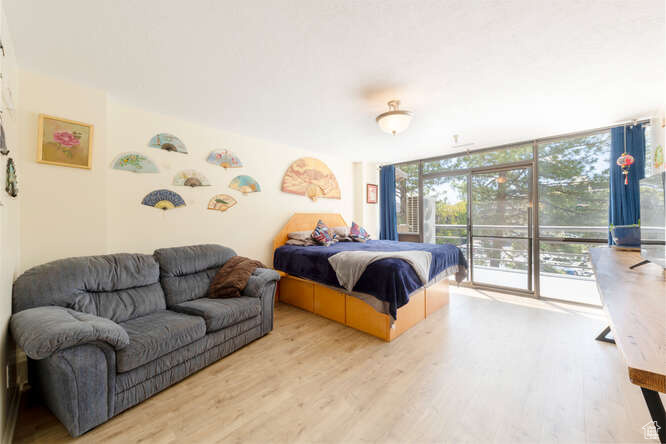 Bedroom featuring expansive windows, access to outside, and light wood-style flooring