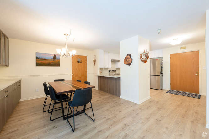 Dining space with a chandelier, light wood finished floors, and baseboards