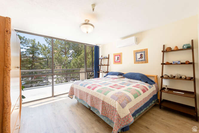 Bedroom featuring a wall unit AC, wood finished floors, and floor to ceiling windows