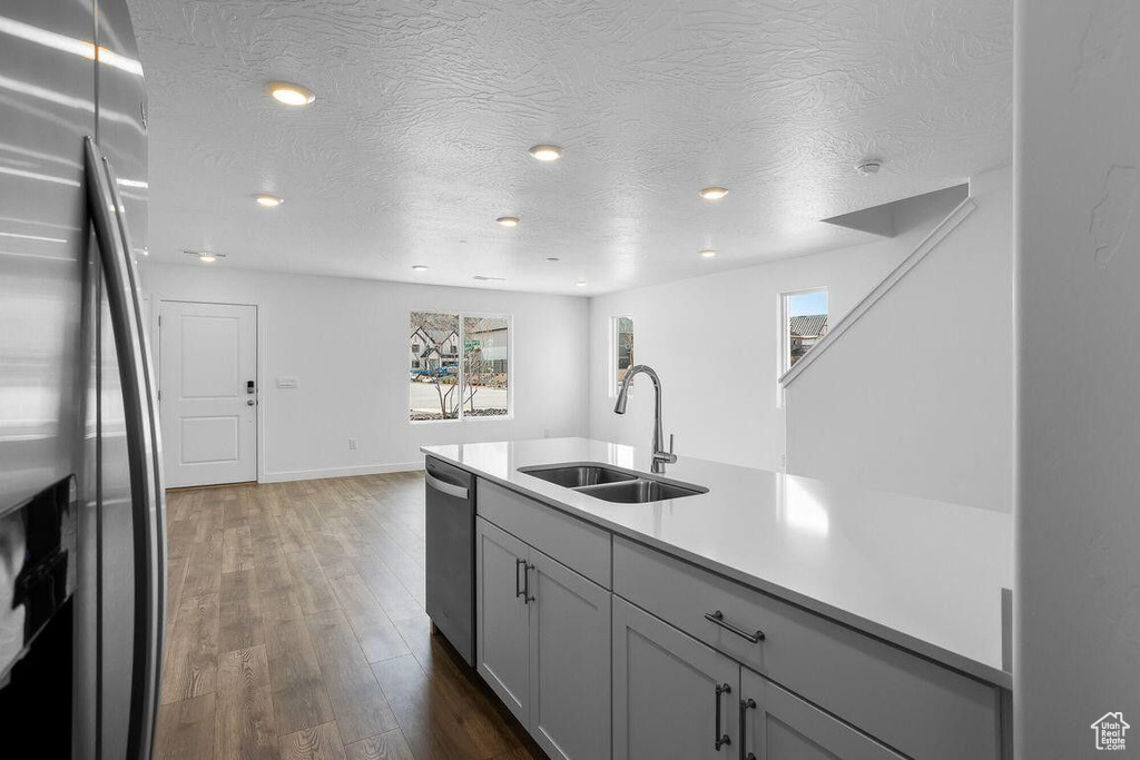 Kitchen featuring dark wood-style flooring, stainless steel appliances, a textured ceiling, light countertops, and a sink