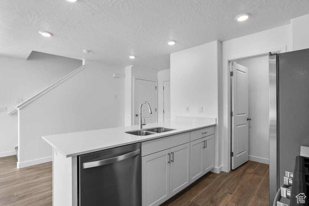Kitchen with dark wood-style floors, stainless steel appliances, a peninsula, and a sink