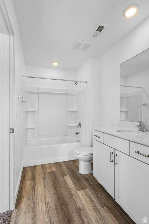 Full bath featuring toilet, wood finished floors, vanity, visible vents, and shower / washtub combination