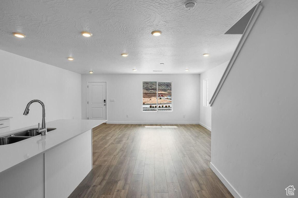Kitchen with a textured ceiling, dark wood finished floors, a sink, and light countertops