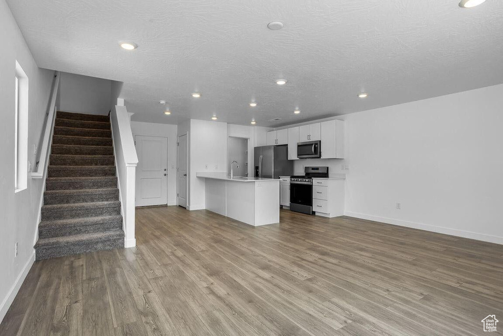 Kitchen with a peninsula, stainless steel appliances, wood finished floors, and open floor plan