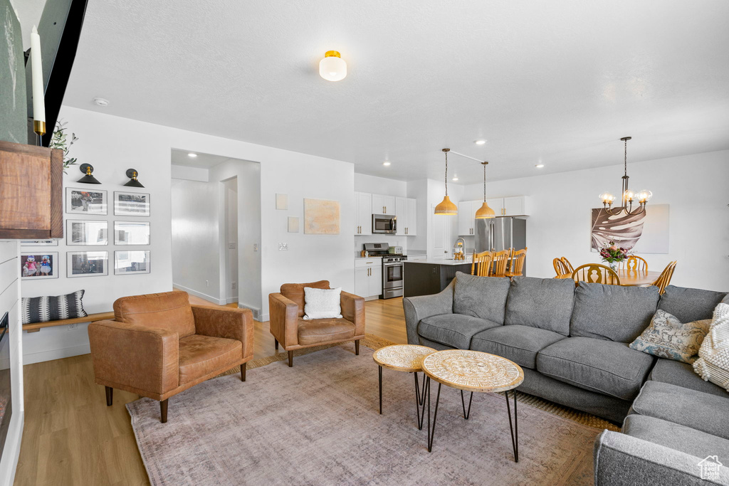 Living room featuring light wood finished floors, recessed lighting, baseboards, and an inviting chandelier