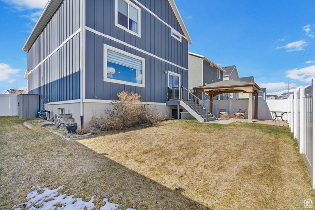 Back of property featuring a yard, a patio, a gazebo, board and batten siding, and a fenced backyard