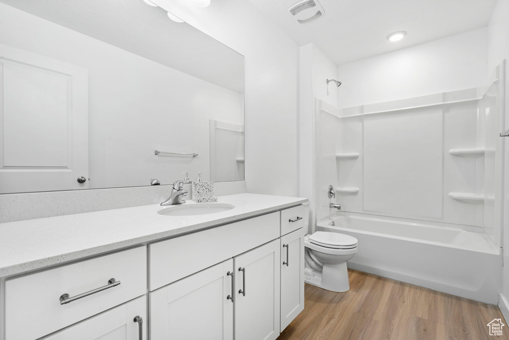 Bathroom featuring bathtub / shower combination, toilet, wood finished floors, vanity, and visible vents