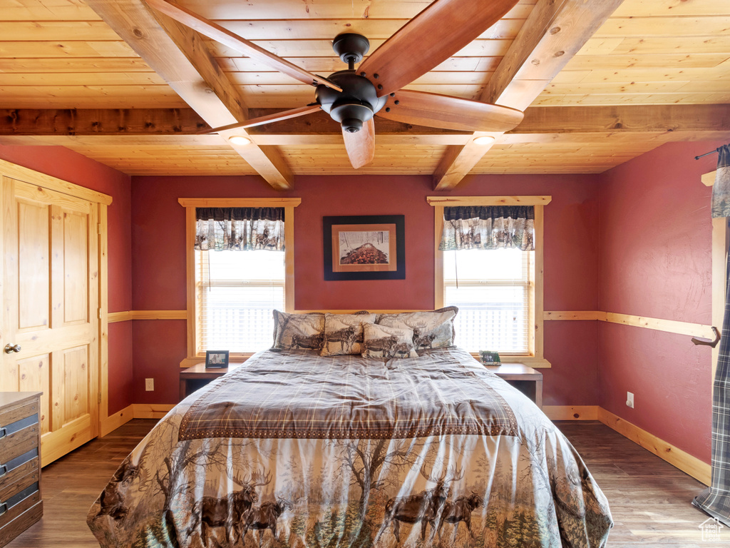 Bedroom with wood ceiling with exposed beams, multiple windows, baseboards, and wood finished floors