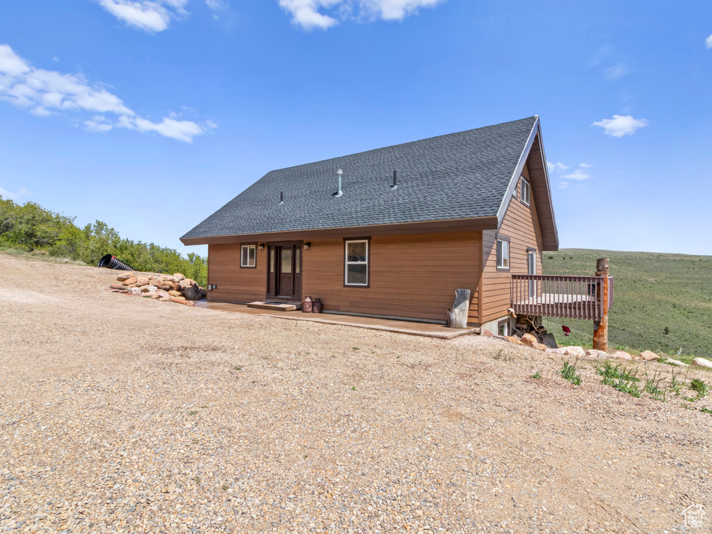 Rear view of house with roof with shingles and a deck