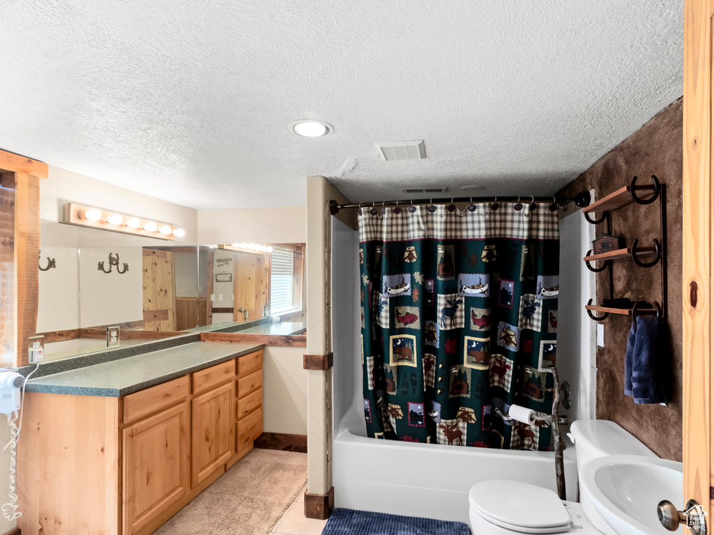Bathroom with a textured ceiling, vanity, shower / bath combination with curtain, toilet, and tile patterned floors
