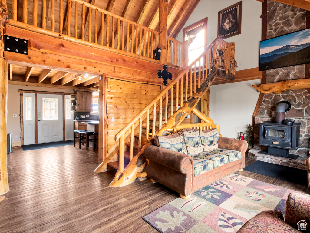 Living area with stairs, a wood stove, wood finished floors, and high vaulted ceiling