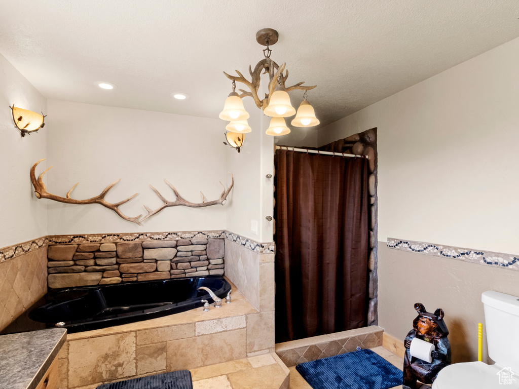 Full bathroom with toilet, a chandelier, a garden tub, and a shower with curtain