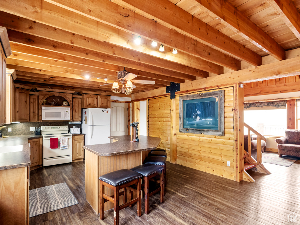 Kitchen with white appliances, a kitchen island, dark wood-style flooring, a kitchen bar, and a sink