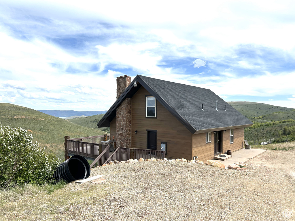 View of front of house with a chimney, a deck with mountain view, and roof with shingles