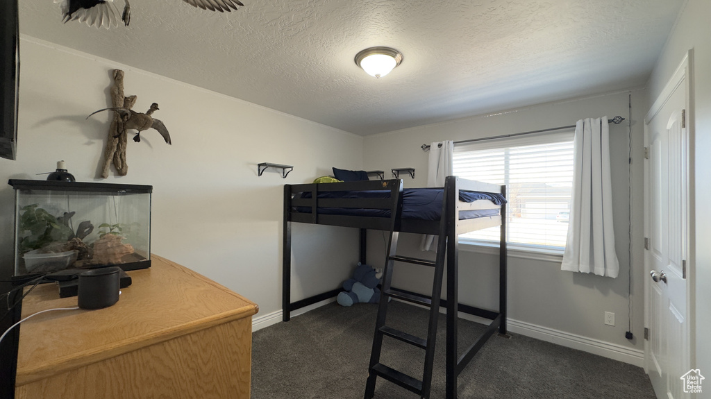 Bedroom featuring a textured ceiling, dark colored carpet, and baseboards