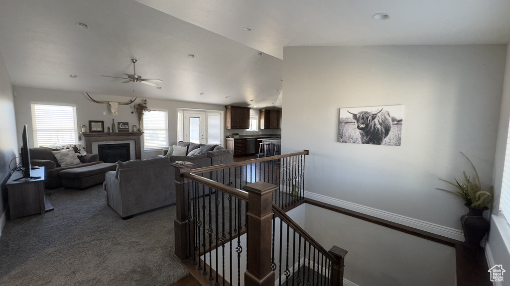 Carpeted living area featuring a fireplace, baseboards, and a ceiling fan