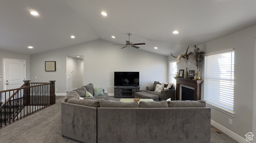 Carpeted living room with lofted ceiling, baseboards, a fireplace, and visible vents