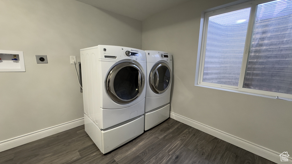 Washroom with laundry area, dark wood finished floors, washer and clothes dryer, and baseboards