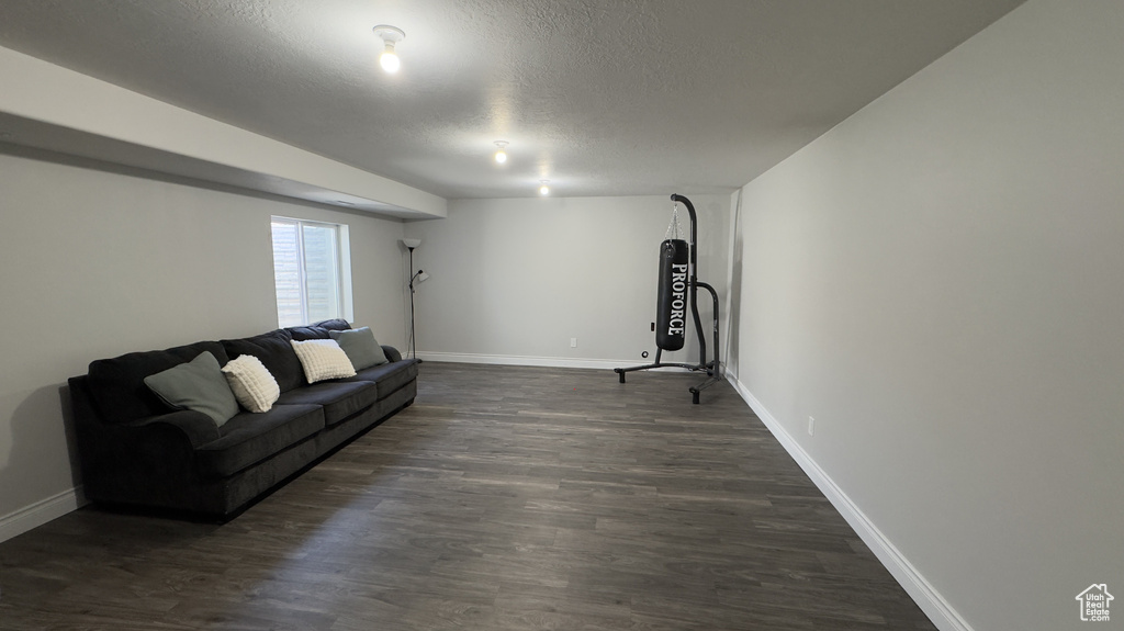 Living area featuring dark wood-type flooring, a textured ceiling, and baseboards