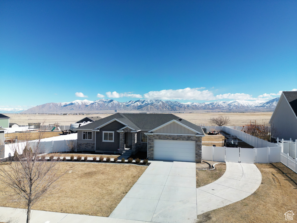View of front of house with driveway, an attached garage, fence private yard, and a mountain view