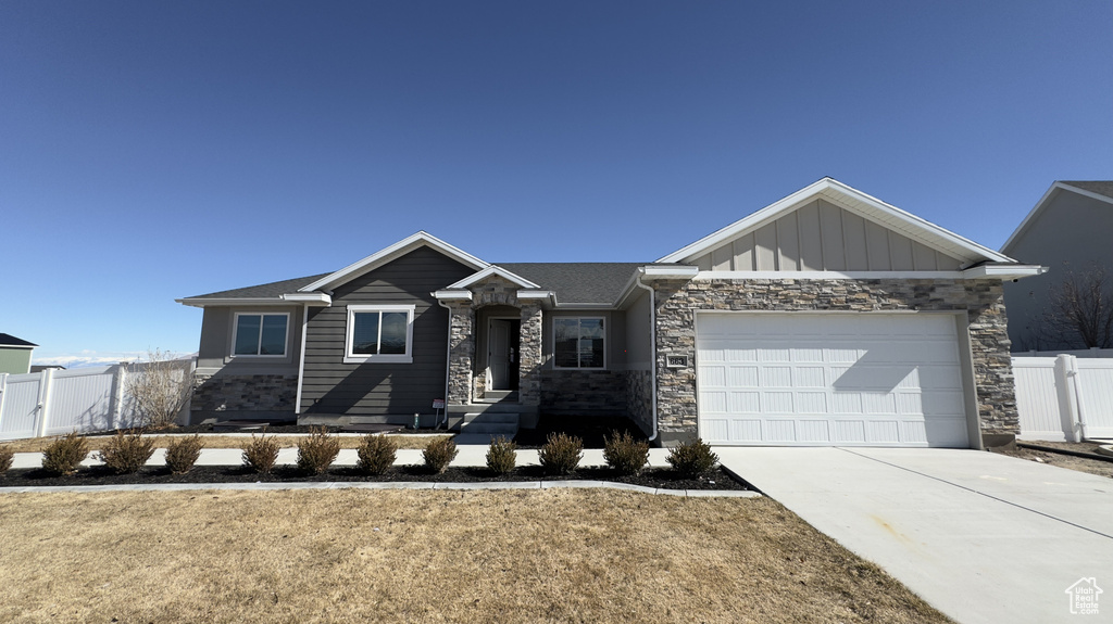View of front facade with a garage, concrete driveway, a gate, fence, and board and batten siding