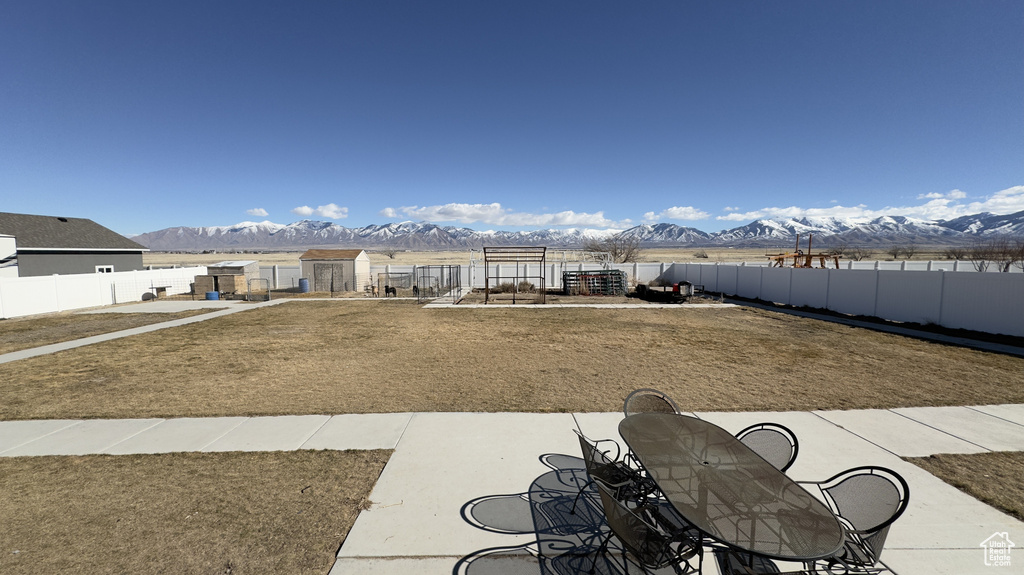 View of yard featuring outdoor dining area, a fenced backyard, a mountain view, and a patio