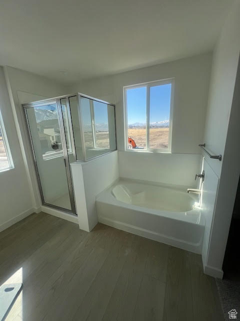 Full bath featuring a stall shower, a garden tub, and wood finished floors