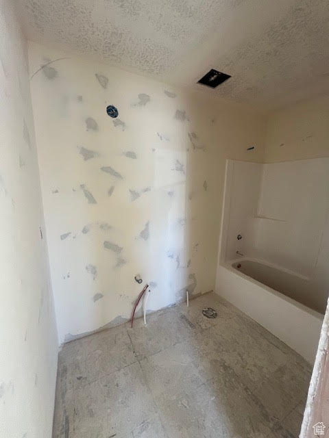 Bathroom with shower / tub combination and a textured ceiling