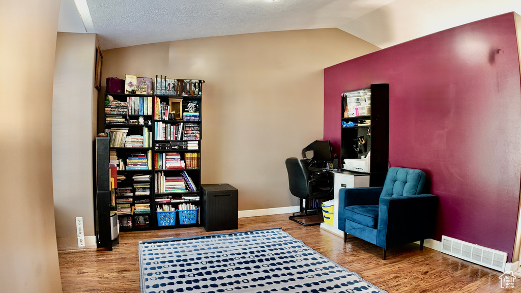 Home office with wood finished floors, lofted ceiling, and baseboards