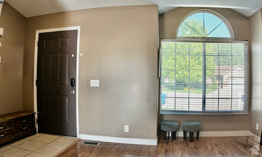 Entryway featuring baseboards, light wood-type flooring, and vaulted ceiling