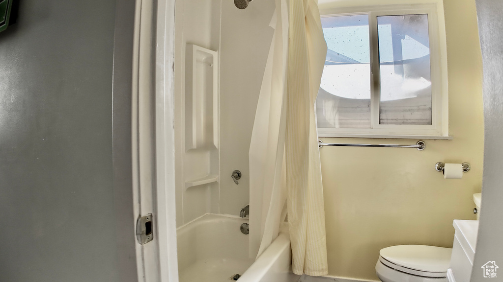 Bathroom featuring toilet, shower / bath combo, and vanity