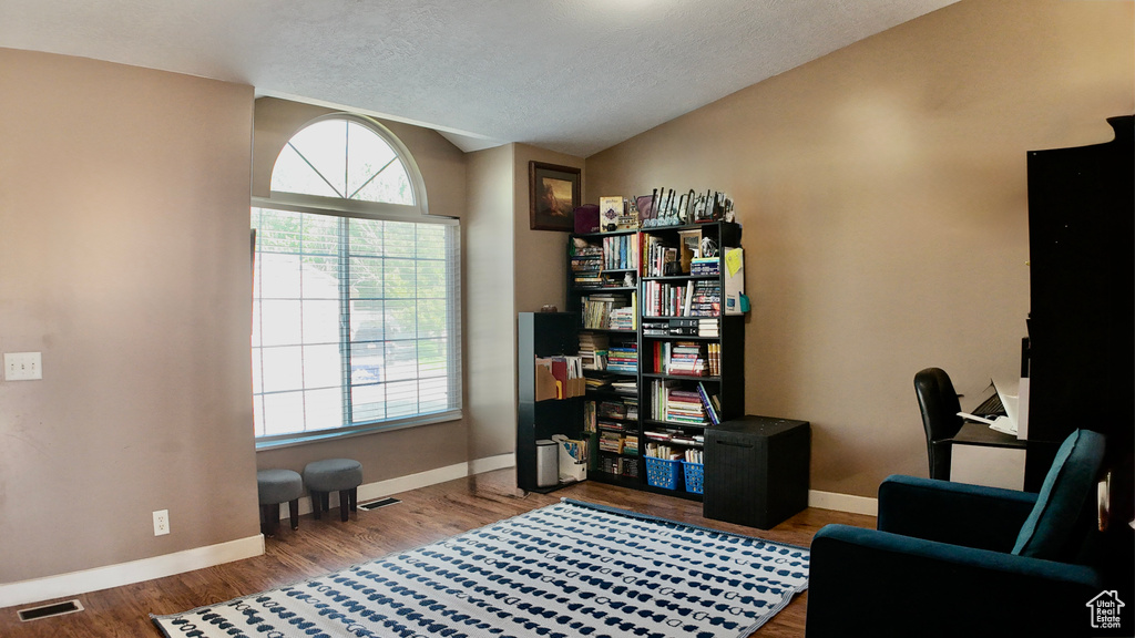 Office featuring lofted ceiling, baseboards, wood finished floors, and a textured ceiling