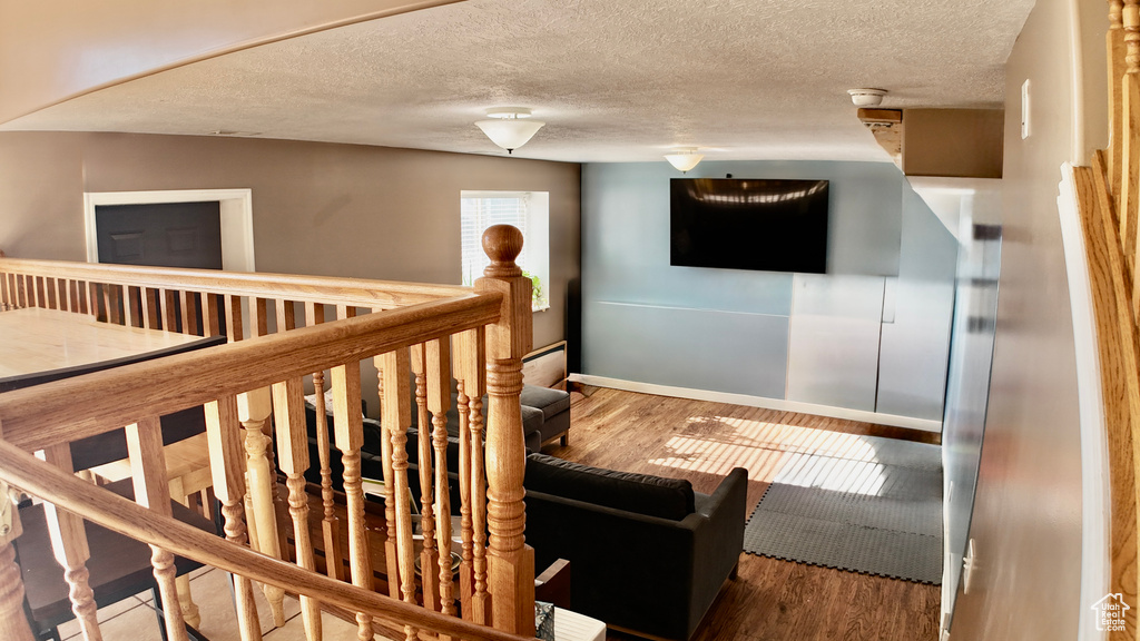 Stairs featuring wood finished floors, a textured ceiling, and baseboards
