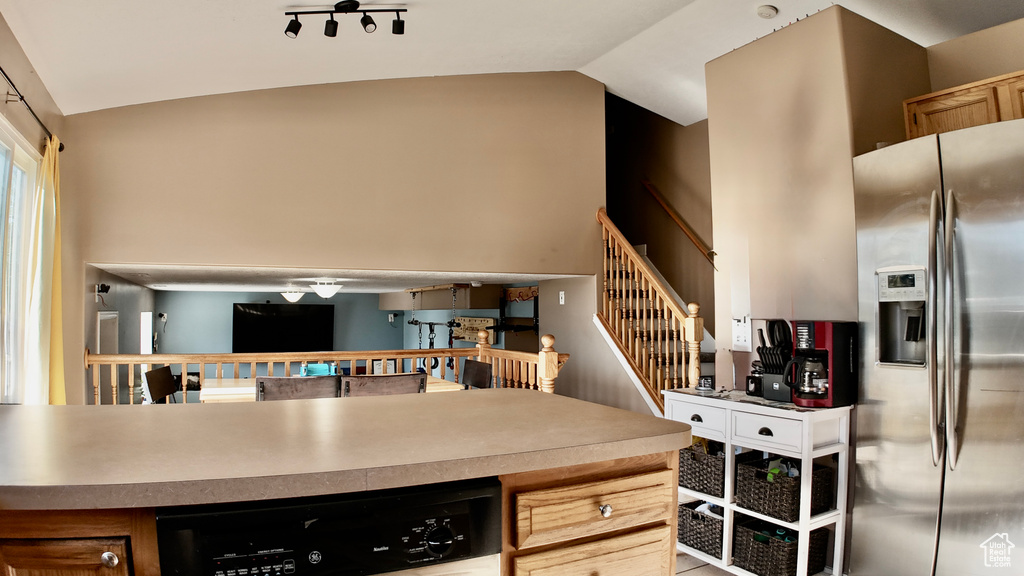 Kitchen featuring stainless steel fridge with ice dispenser, vaulted ceiling, and dishwasher