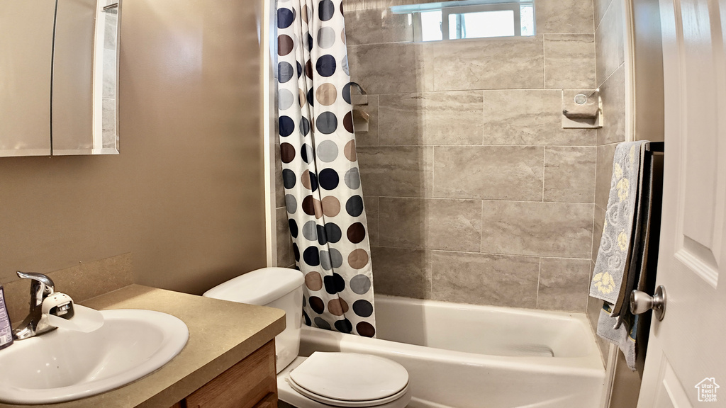 Bathroom with toilet, shower / bath combo with shower curtain, and vanity