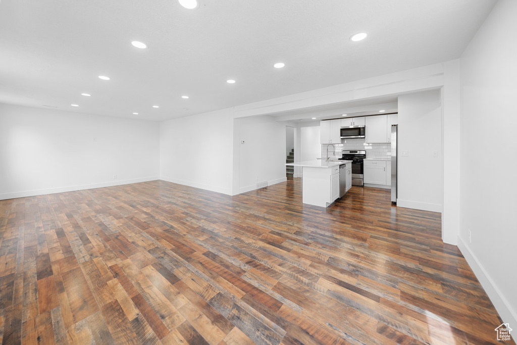 Unfurnished living room with recessed lighting and dark wood-style floors