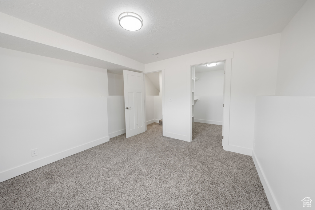 Unfurnished bedroom featuring carpet, a spacious closet, and a closet
