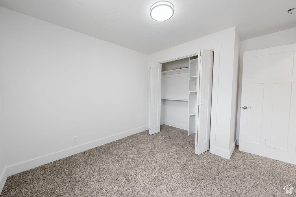 Unfurnished bedroom with light carpet and a closet