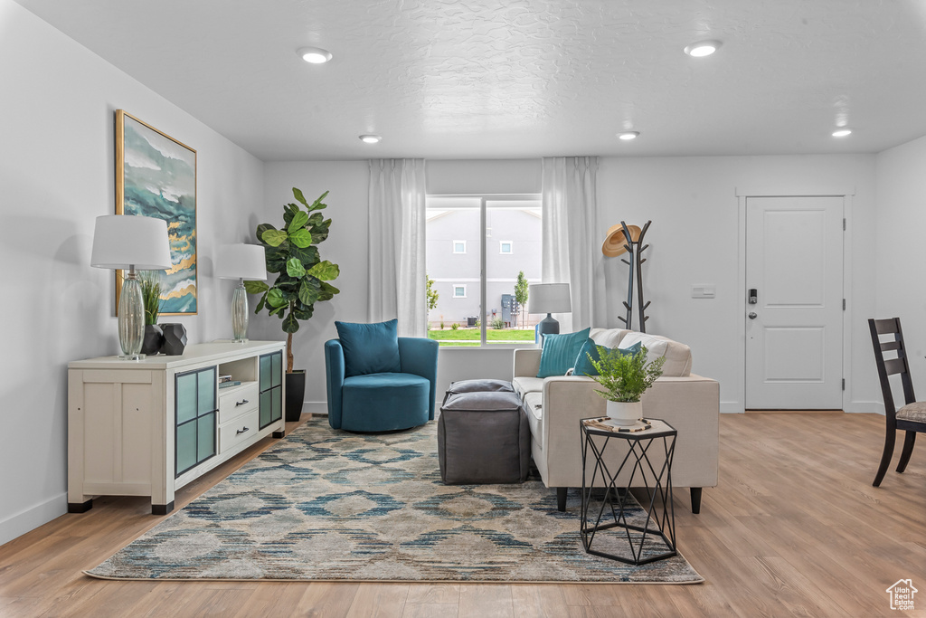 Living area with baseboards, a textured ceiling, recessed lighting, and light wood-style floors