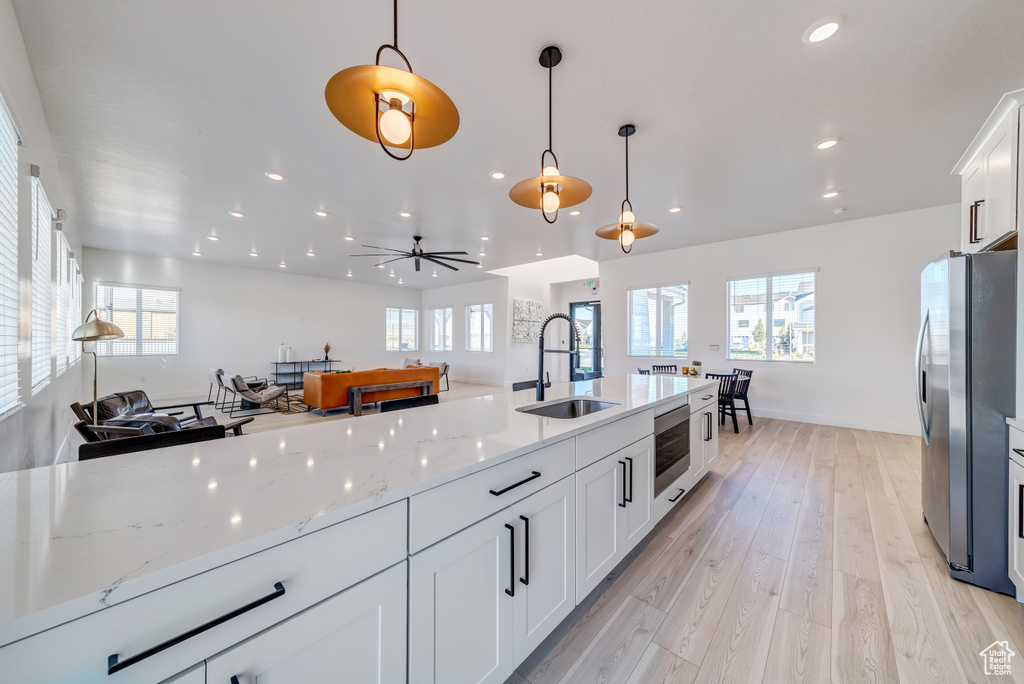 Kitchen featuring freestanding refrigerator, pendant lighting, white cabinetry, and a sink