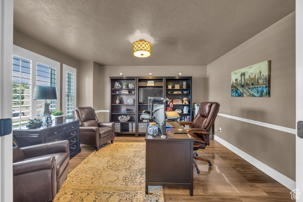 Office area with wood finished floors, a textured ceiling, and baseboards
