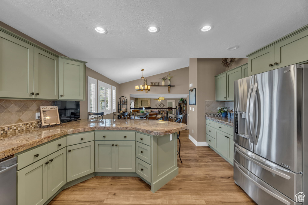 Kitchen featuring green cabinets, stainless steel appliances, a peninsula, vaulted ceiling, and a chandelier