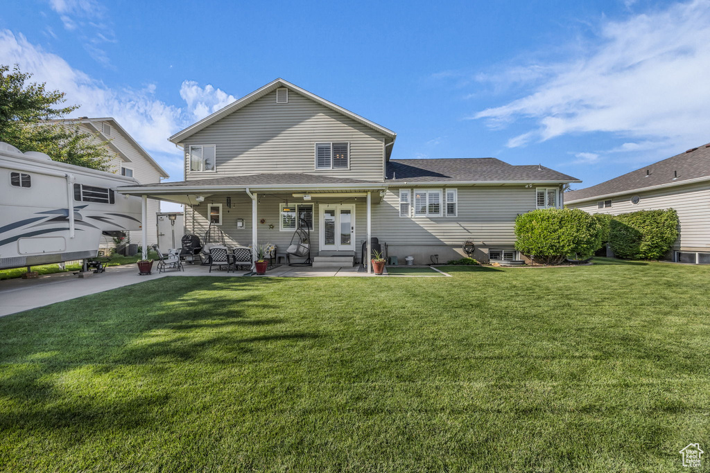 Rear view of house featuring a yard, a patio area, a shingled roof, and french doors