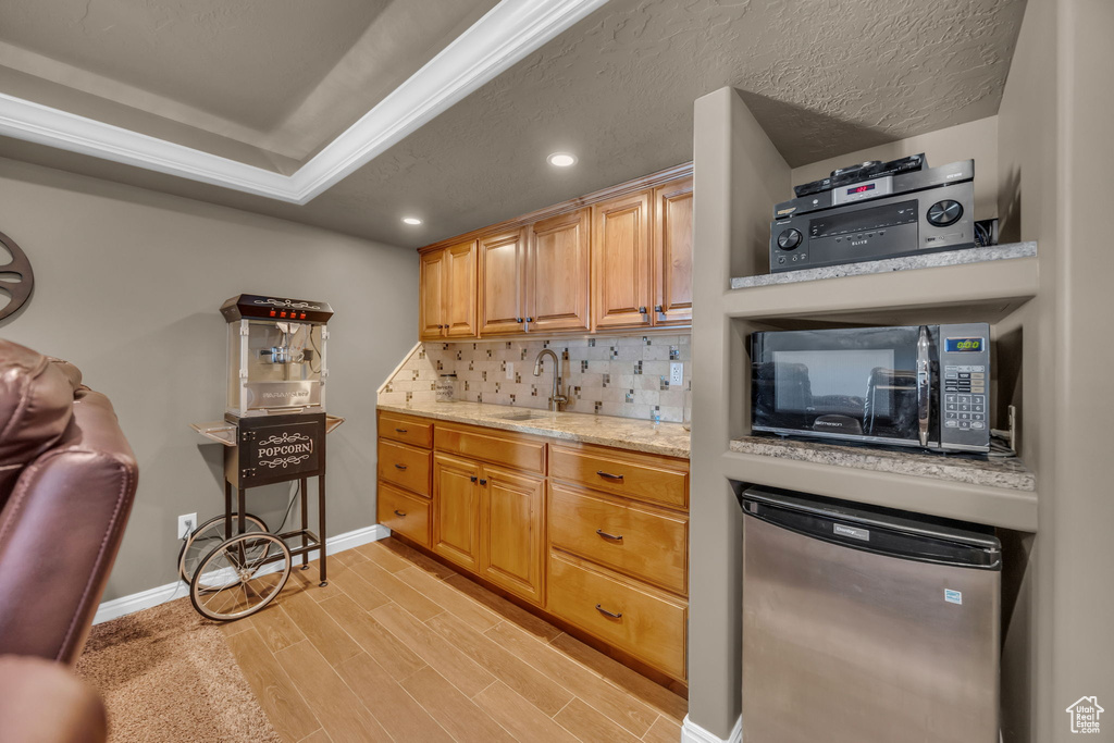 Kitchen with black microwave, light wood-style flooring, fridge, recessed lighting, and a sink
